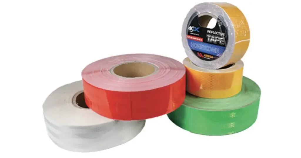 High-visibility reflective tape applied to a dark metal bollard, glowing brightly as it catches the light from an approaching vehicle’s headlights